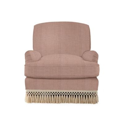 Pink upholstered armchair with rounded armrests and a wide seat, featuring a decorative cream fringe along the bottom edge. Get the Serena and Lily look for less with this chic and stylish piece.
