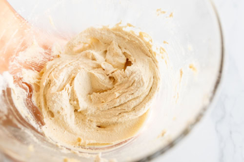 A glass bowl containing creamed butter and sugar, mixed until smooth and light in color.