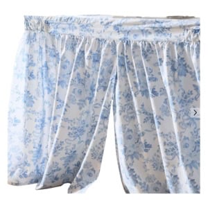Light blue and white floral-patterned curtain panels gathered at the top with a ruffled edge, hanging from a horizontal rod.