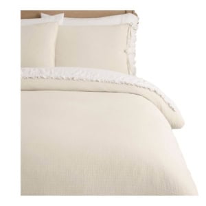 Cream-colored bedding set with a textured duvet cover and matching pillowcases, shown neatly arranged on a bed with a wooden headboard.