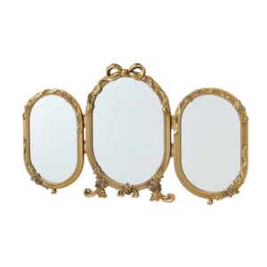 A gold-framed three-panel vanity mirror with ornate detailing and a bow design on the central frame.