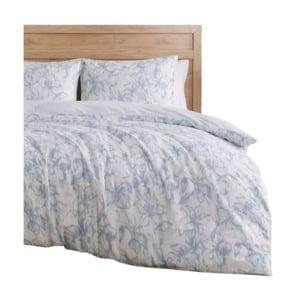 A wooden bed with white and light blue floral-patterned bedding, including a comforter and two pillows.