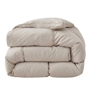 A neatly folded, light beige comforter with a smooth, quilted surface is shown against a plain white background.