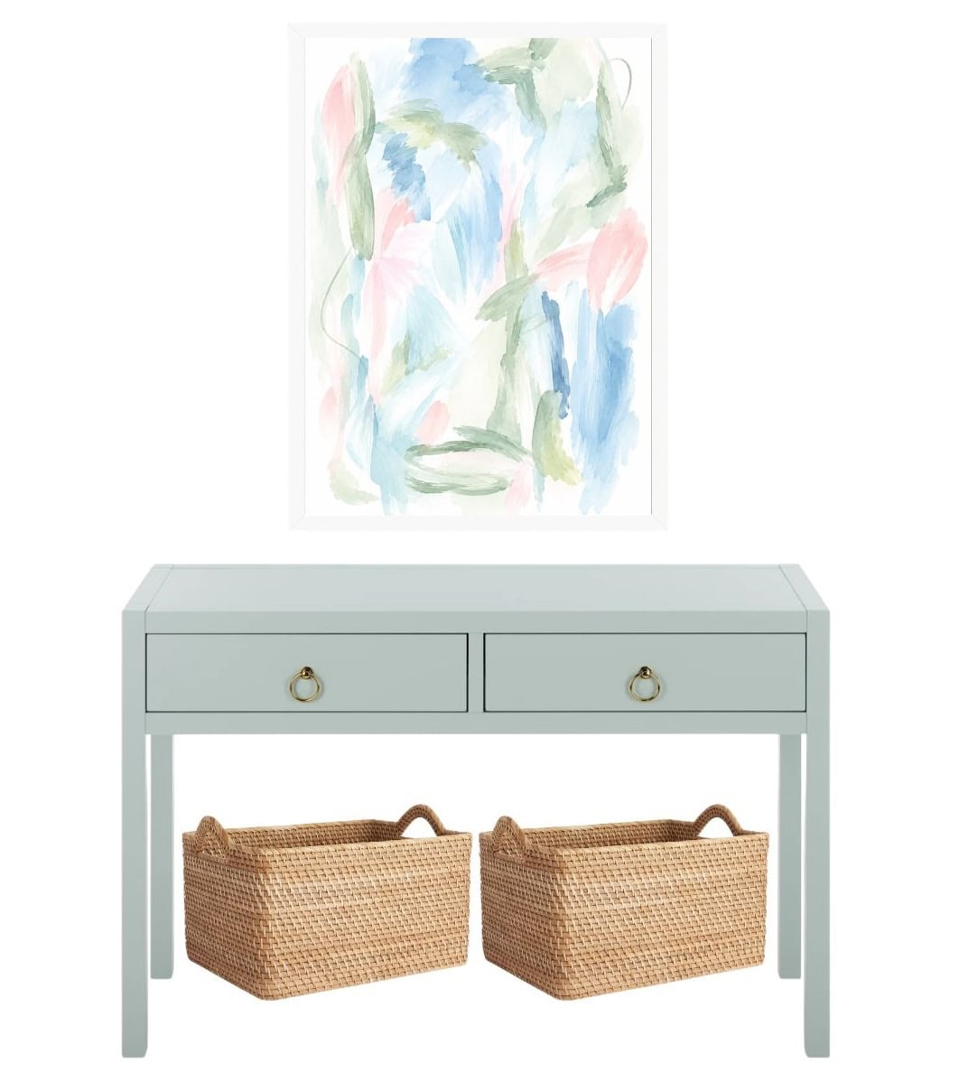 A light blue console table with two drawers and two woven baskets underneath, featuring an abstract watercolor painting in a white frame mounted on the wall above.