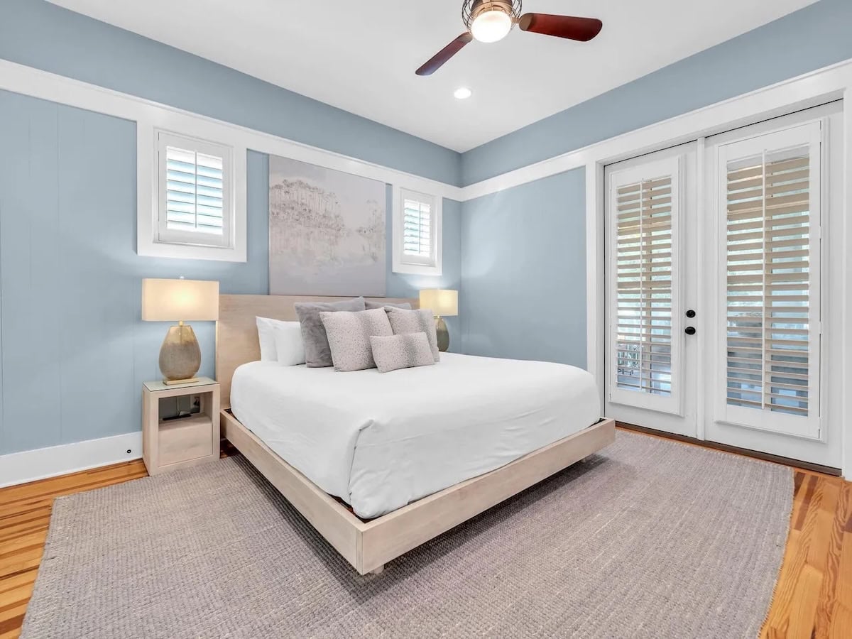 Bedroom with a platform bed, two nightstands with lamps, and glass doors opening to a patio.
