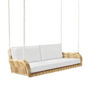 Wicker hanging porch swing with white cushions, suspended by four ropes.